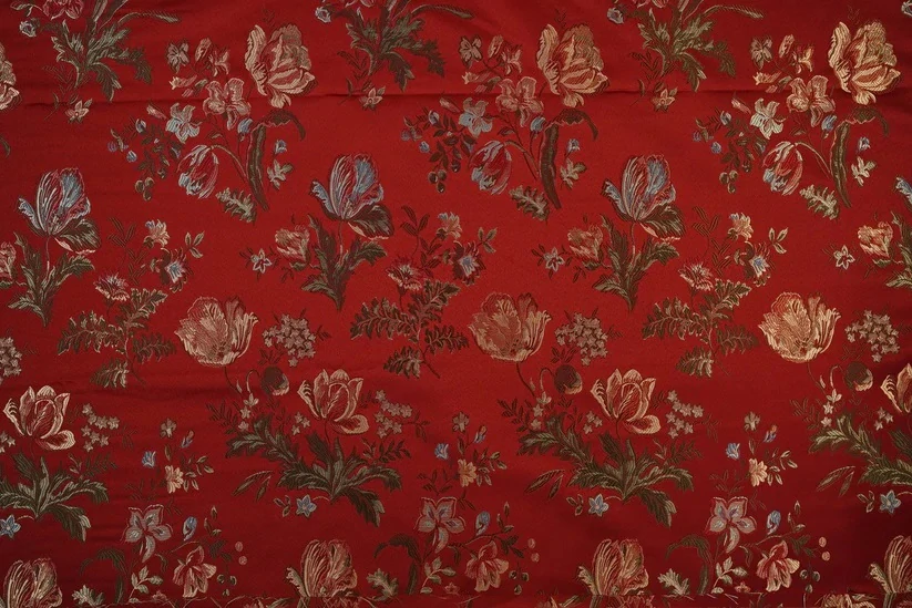 Tkané květy na rubínově červeném podkladu